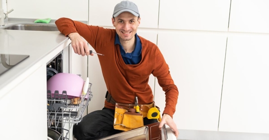 appliance repair technician next to dishwasher